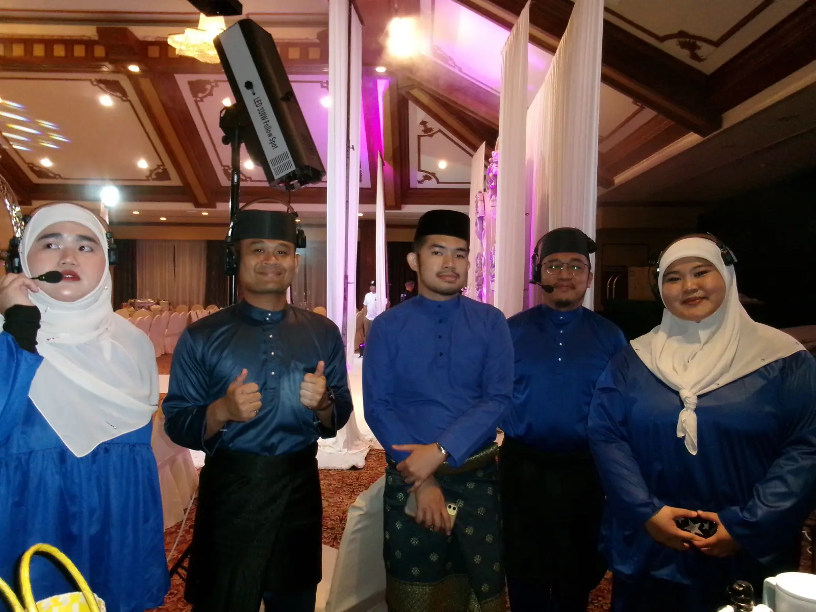 Five Agendas Brunei crew in matching blue, all wearing comms headsets, in a Brunei ballroom